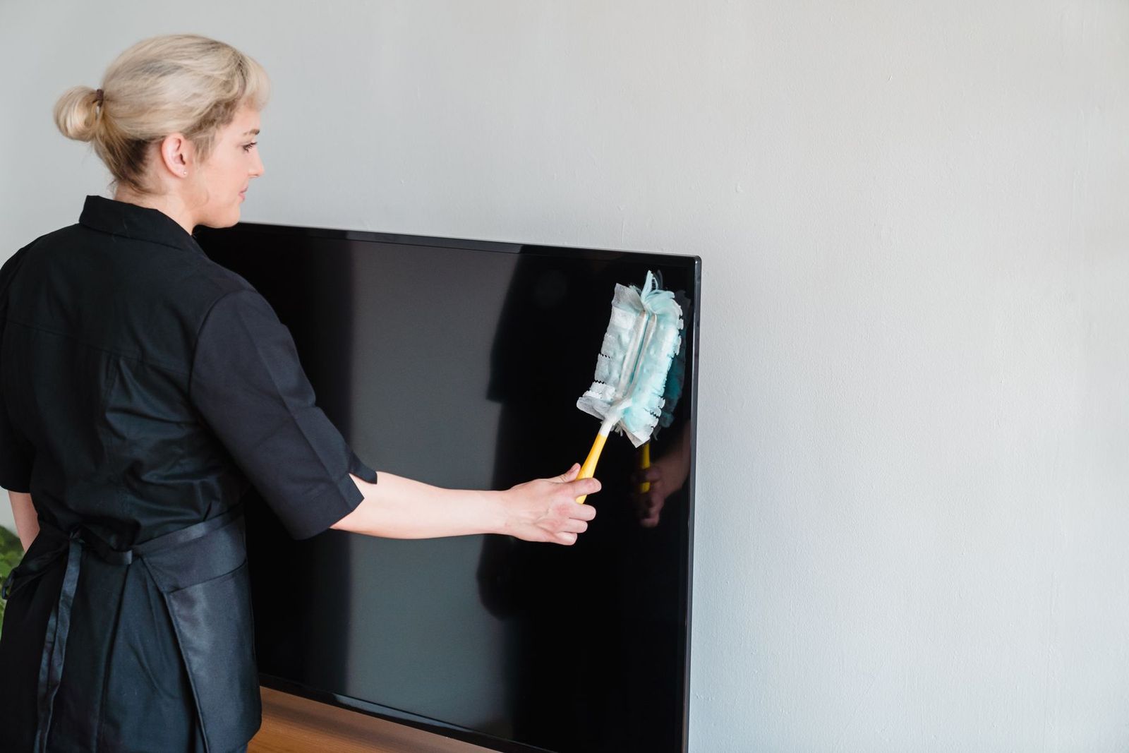 Haushaltskraft wischt Staub vom Fernseher